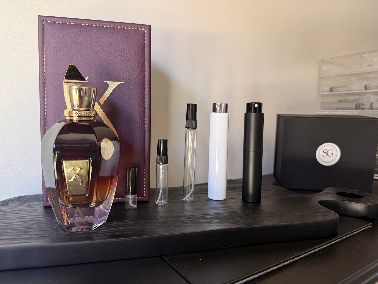 Naxos Perfume bottle next to different sized perfume bottles