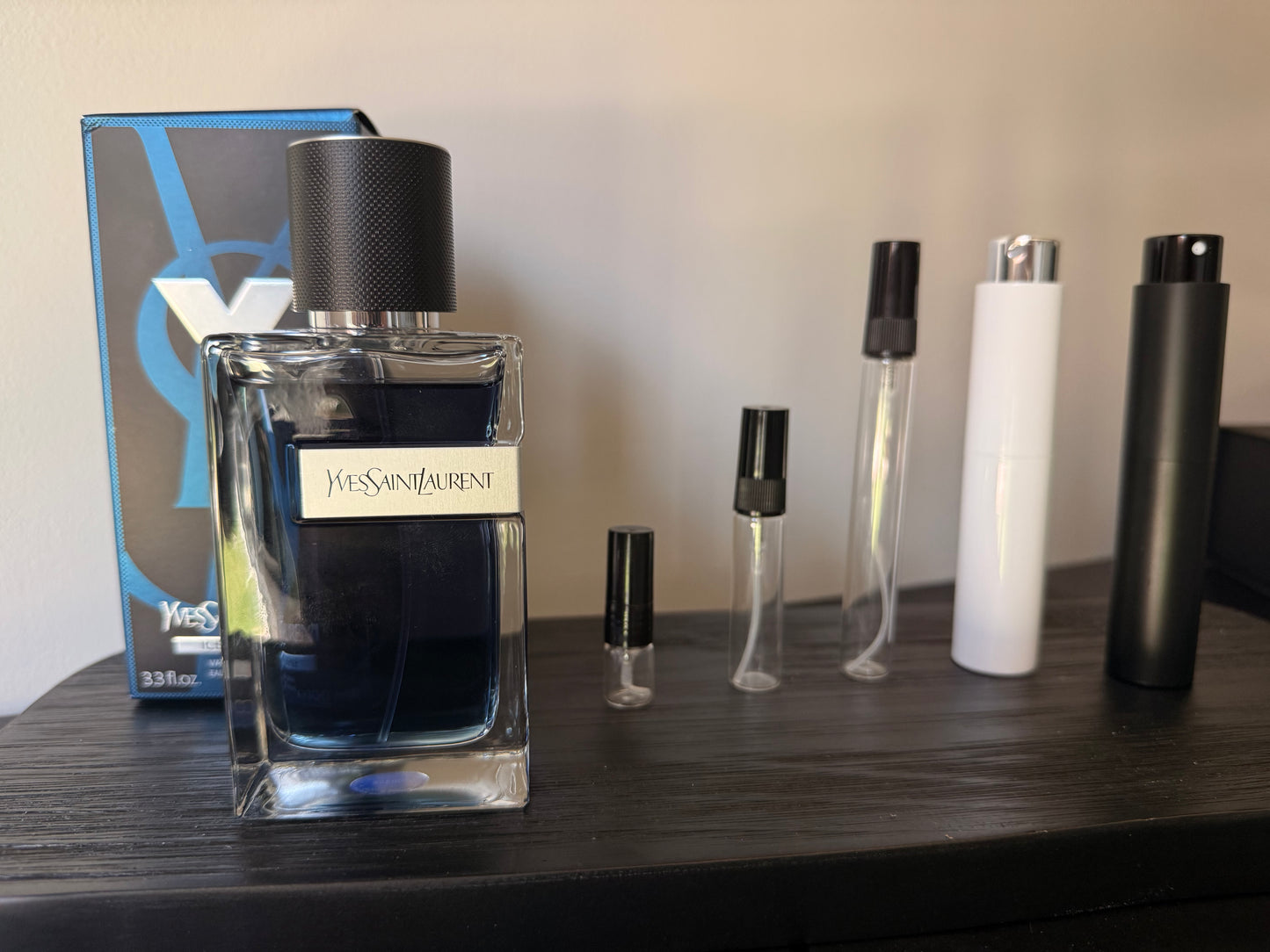 Yves Saint Laurent perfume bottle with smaller bottles and packaging on a wooden surface
