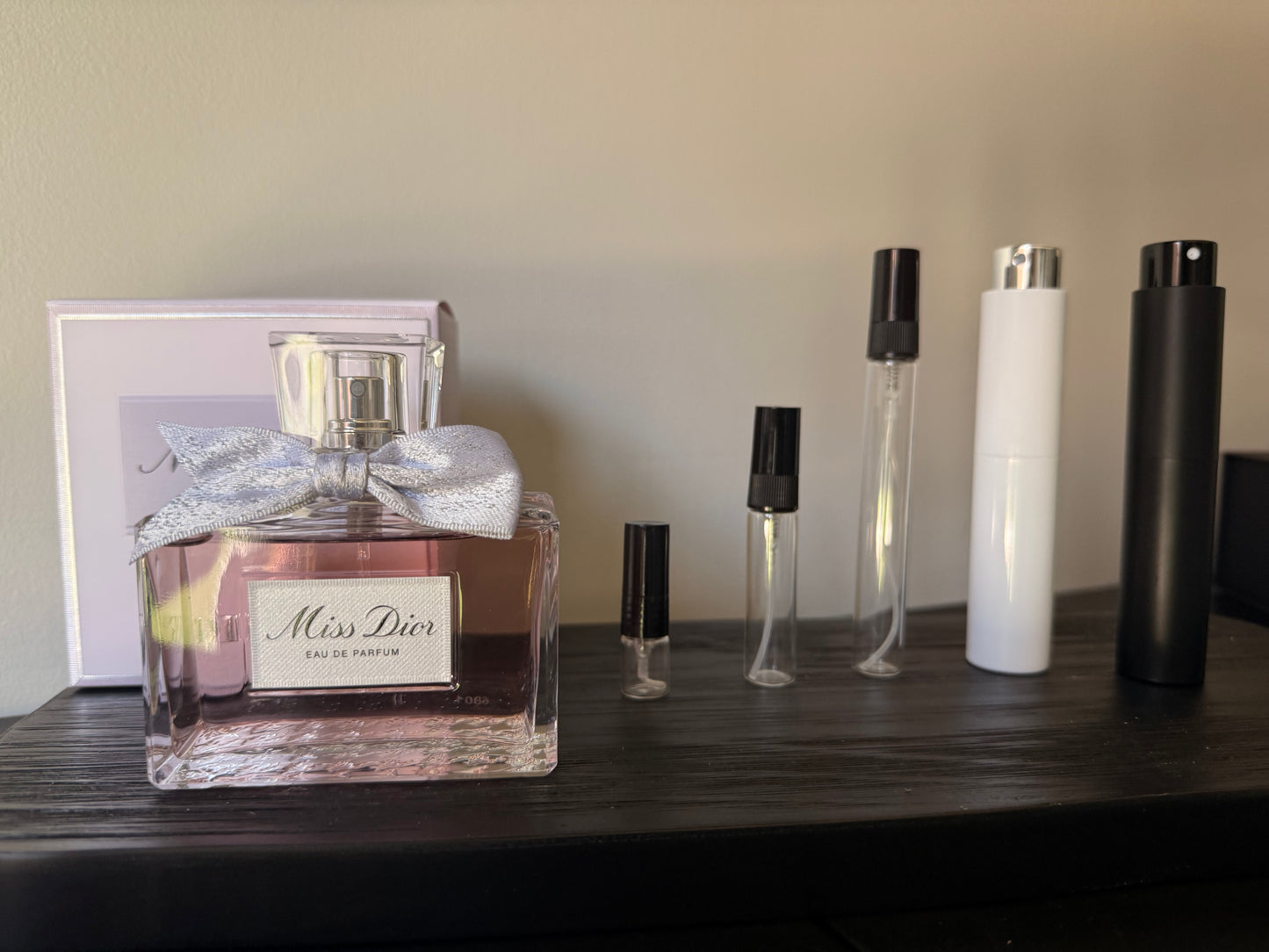 Miss Dior perfume bottle with smaller bottles on a wooden surface