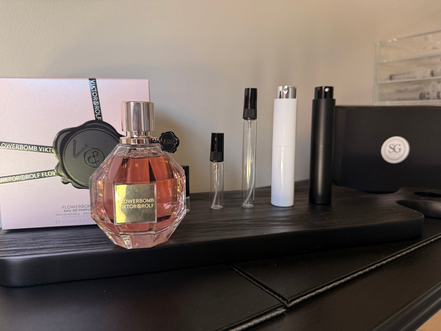 Perfume bottle and travel-sized versions on a black surface with a blurred background