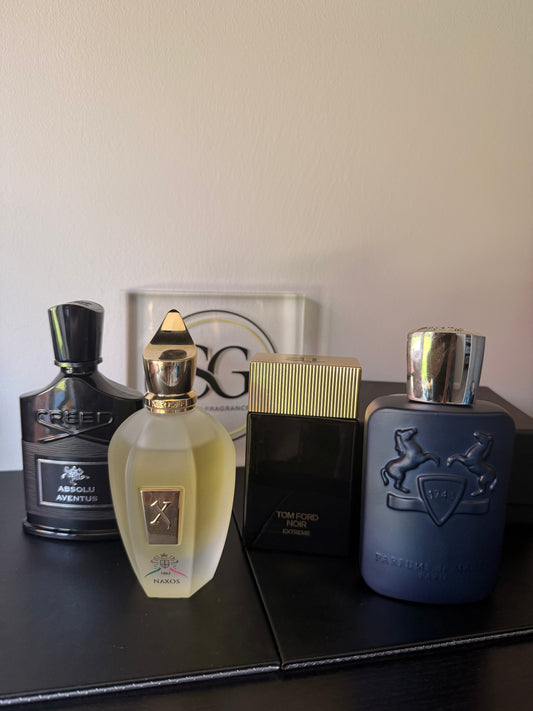 Four perfume bottles on a dark surface with a light background