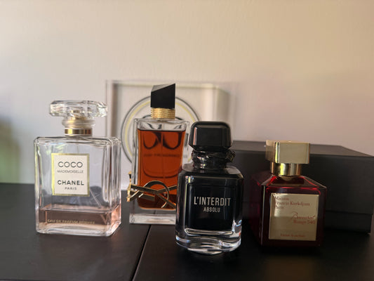 Four perfume bottles on a dark surface with a neutral background
