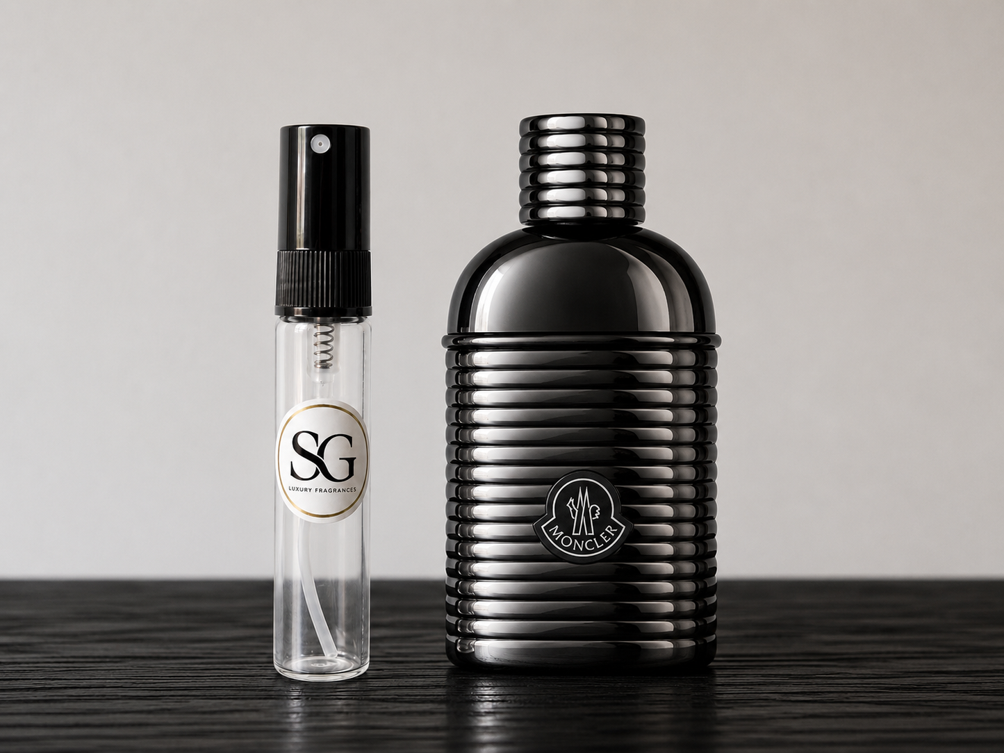 Black perfume bottle and smaller spray bottle on a wooden surface with a neutral background