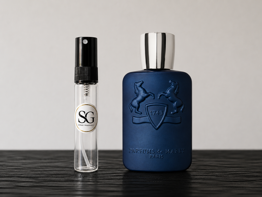 Two perfume bottles, one blue and one clear with black cap, on a wooden surface.