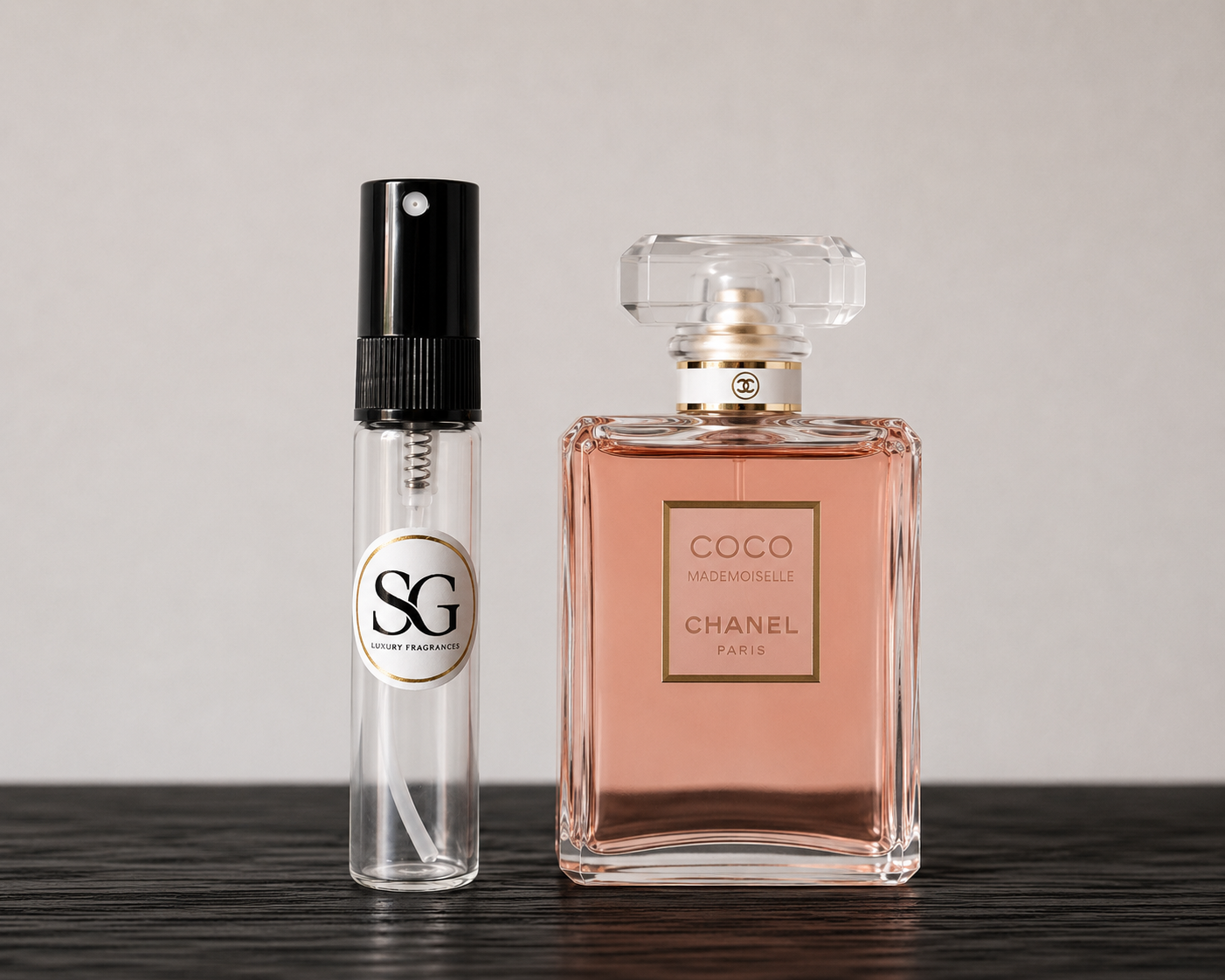 Two perfume bottles, one large and one small, on a wooden surface with a neutral background.