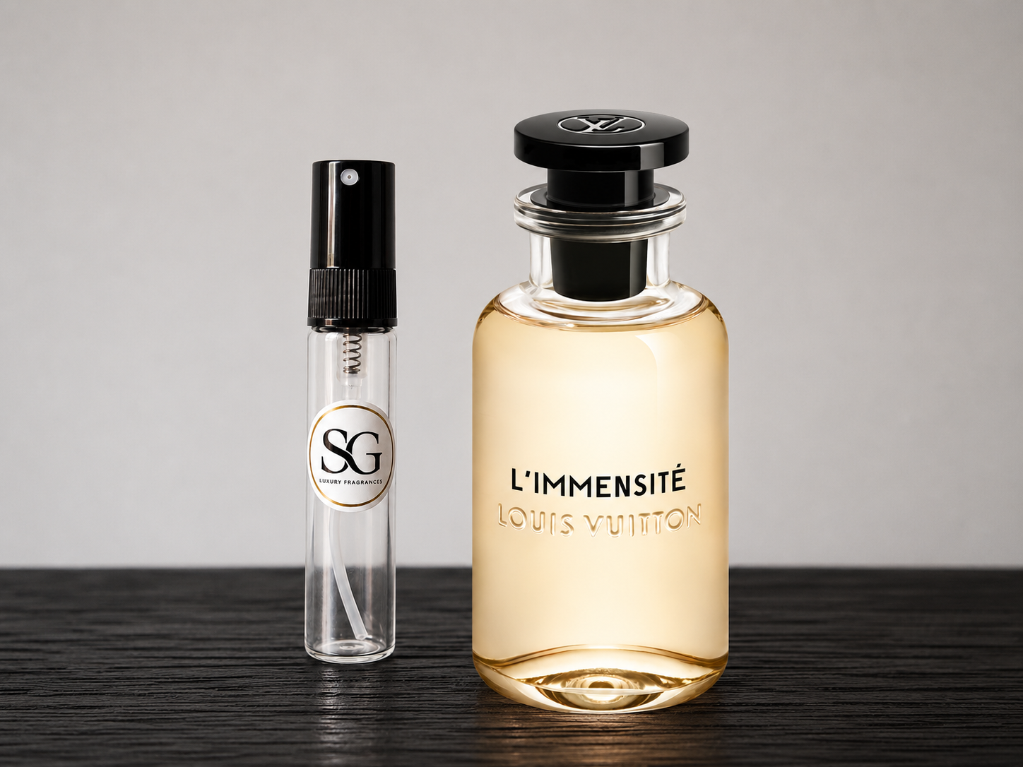 Two perfume bottles, one large and one small, on a wooden surface with a gray background.