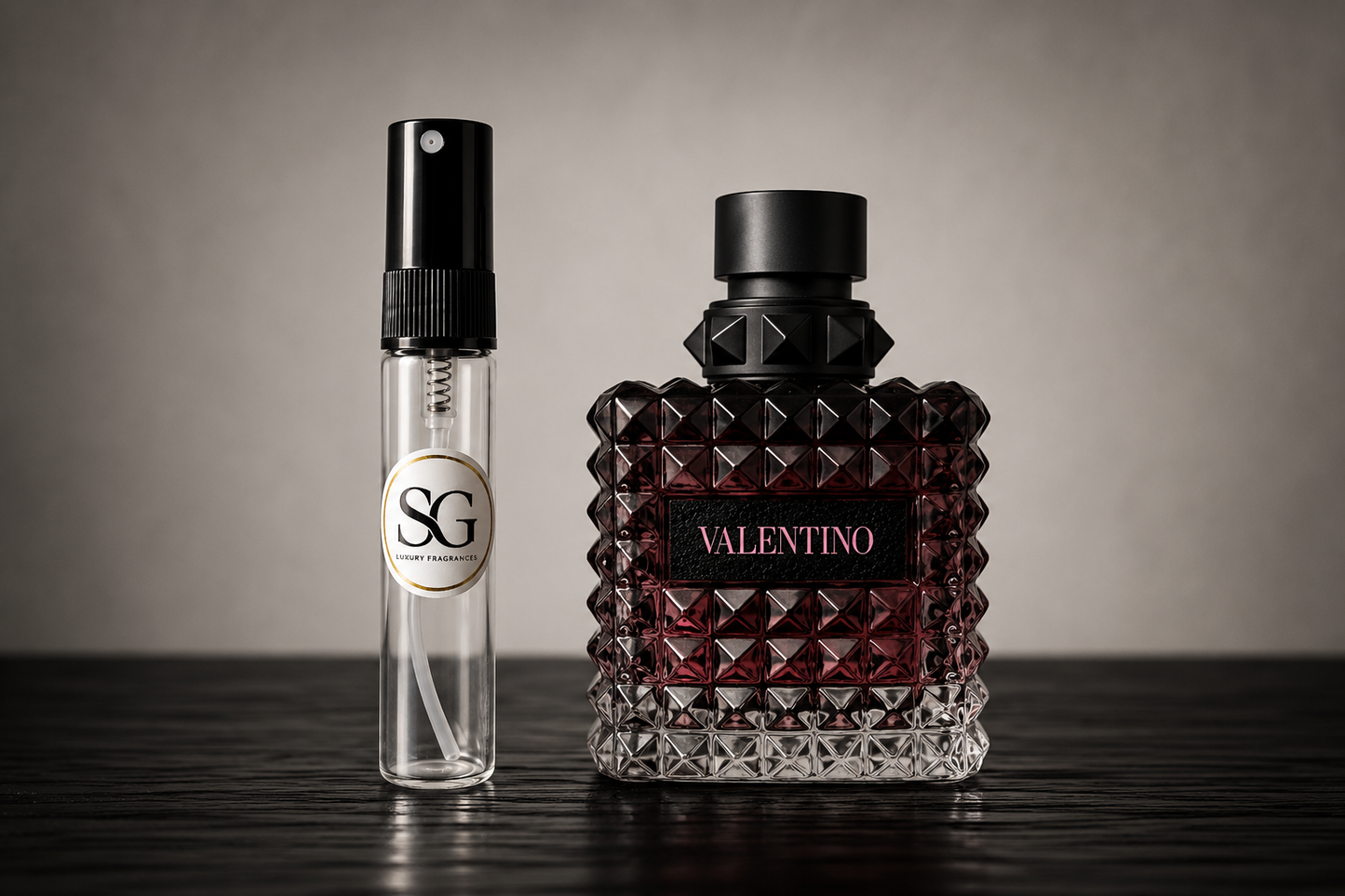 Two perfume bottles, one small and one large, on a reflective surface with a neutral background.