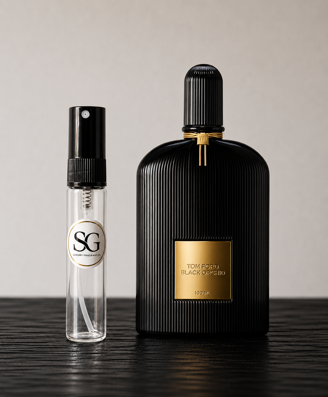 Black perfume bottle with gold accents and a smaller clear bottle on a wooden surface.