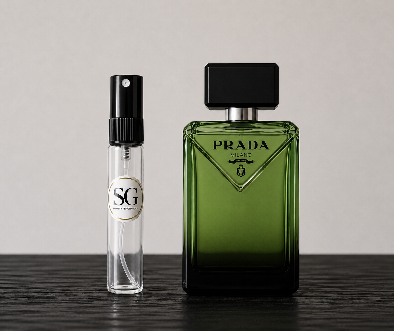 Green Prada perfume bottle and smaller clear bottle with black cap on a dark surface.