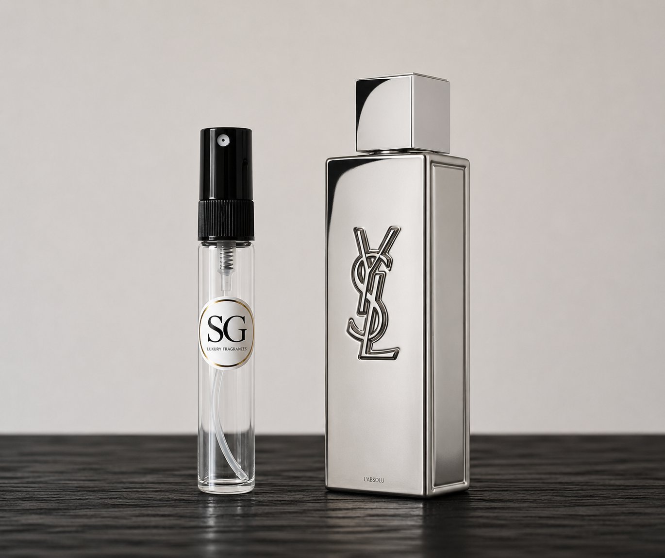 Two perfume bottles, one large and one small, on a dark surface with a light gray background.