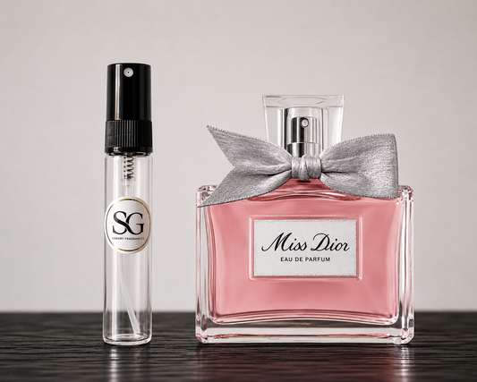 Two perfume bottles, one clear with a black cap and gold logo, the other pink with a silver bow, on a neutral background.