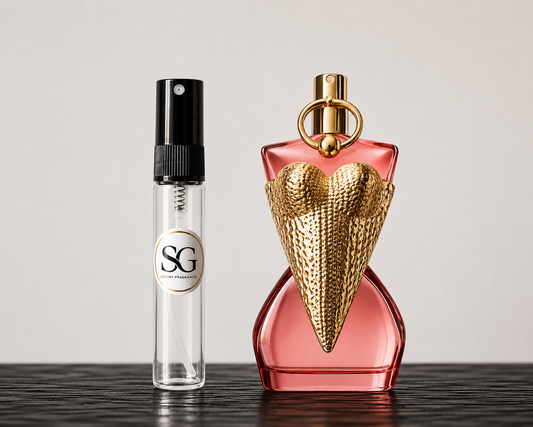 Two perfume bottles, one small and clear with a black spray top and gold logo, the other large and pink with a gold cap and heart-shaped design, on a dark surface.