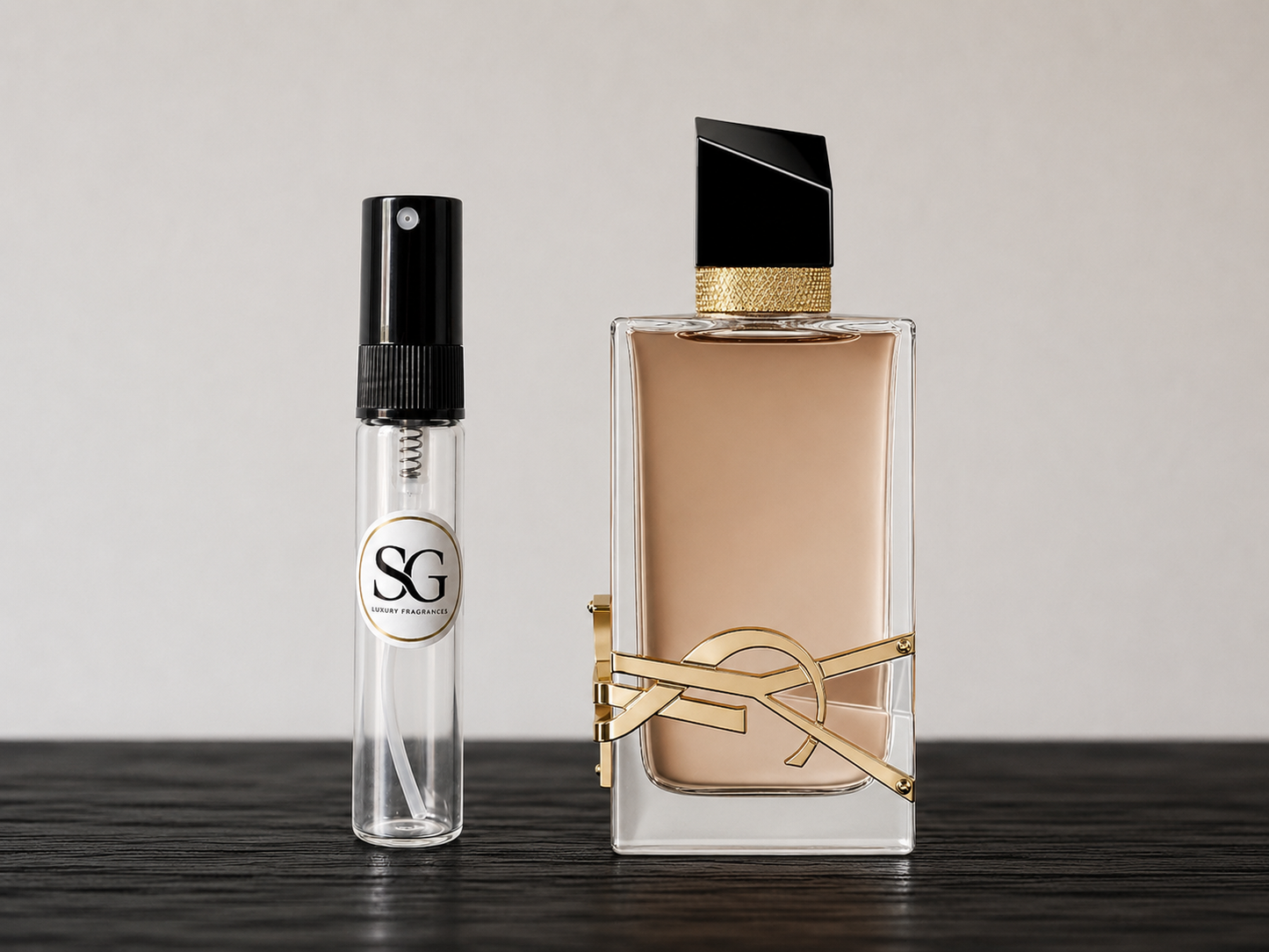 Two perfume bottles, one small and one large, on a wooden surface with a neutral background.