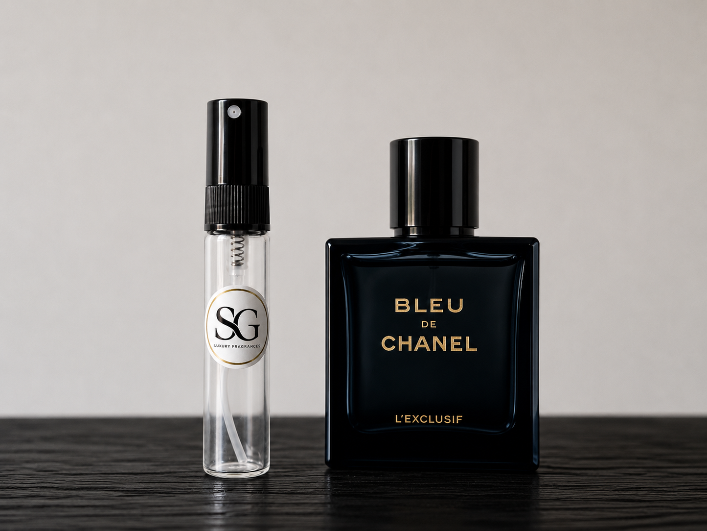 Two perfume bottles, one small and clear with a black cap, and the other large and black with 'Bleu de Chanel' text, on a dark surface.