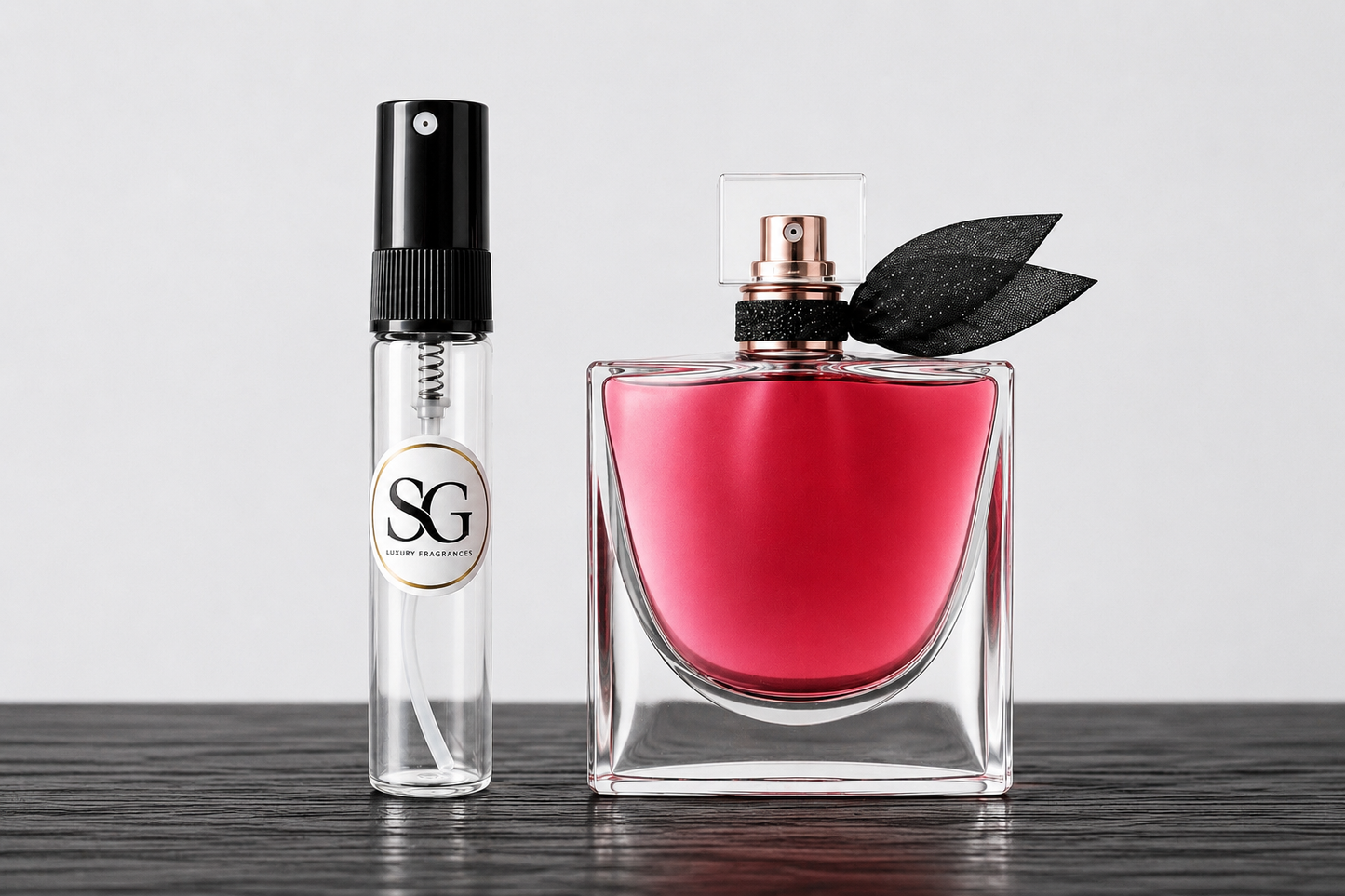 Two perfume bottles, one red and one smaller black and white bottle, on a wooden surface with a light gray background.